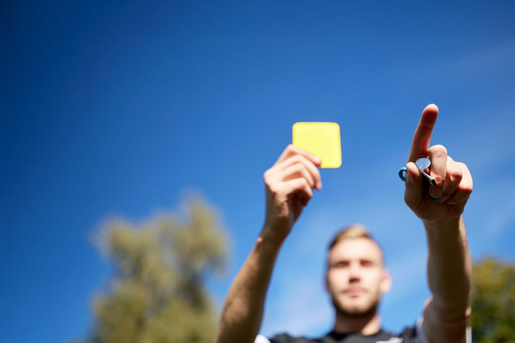 arbitro che alza cartellino giallo durante partita di calcio
